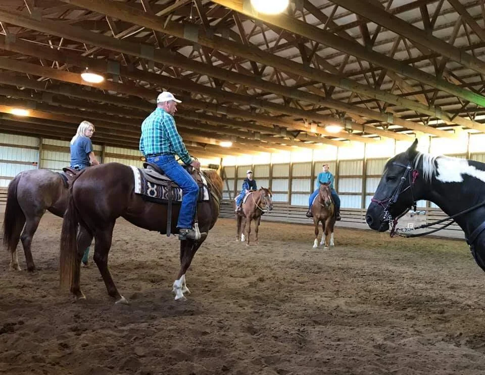Tom Faul riding in the indoor arena with lesson riders at Canyon Equine